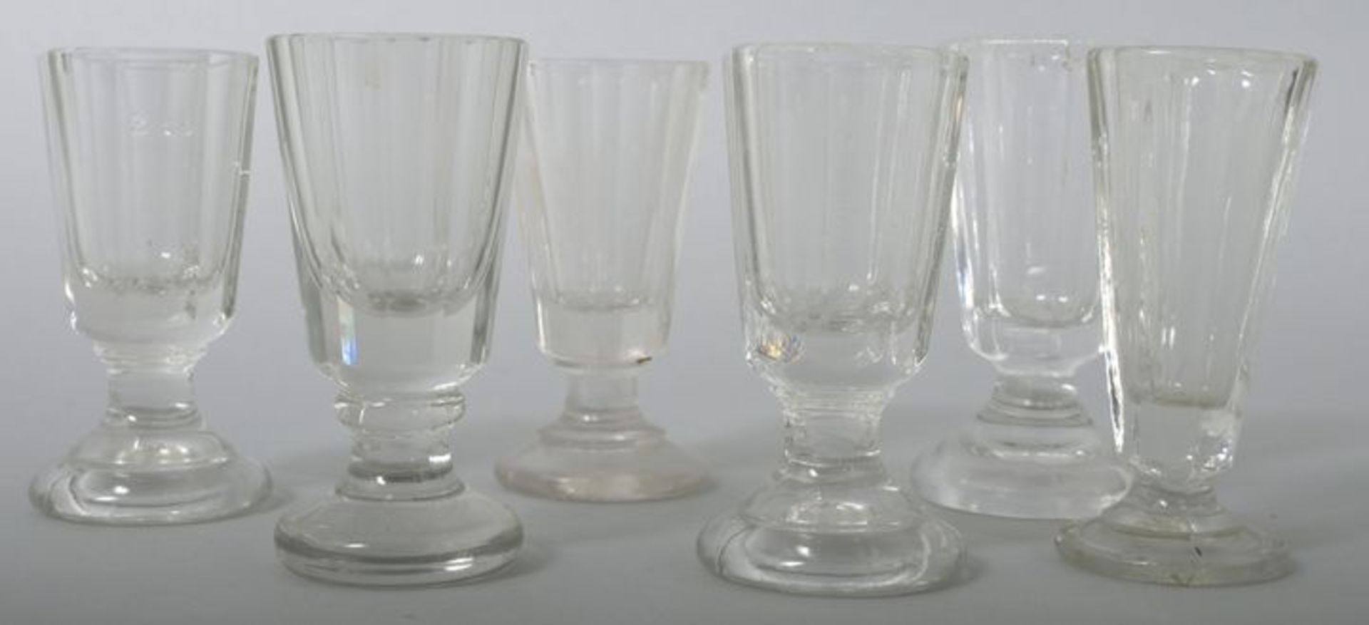 Sechs Schnapsgläser, 20. Jh. Farbloses Pressglas, ein Glas Kristall. Form mit abgesetztem Fuß und