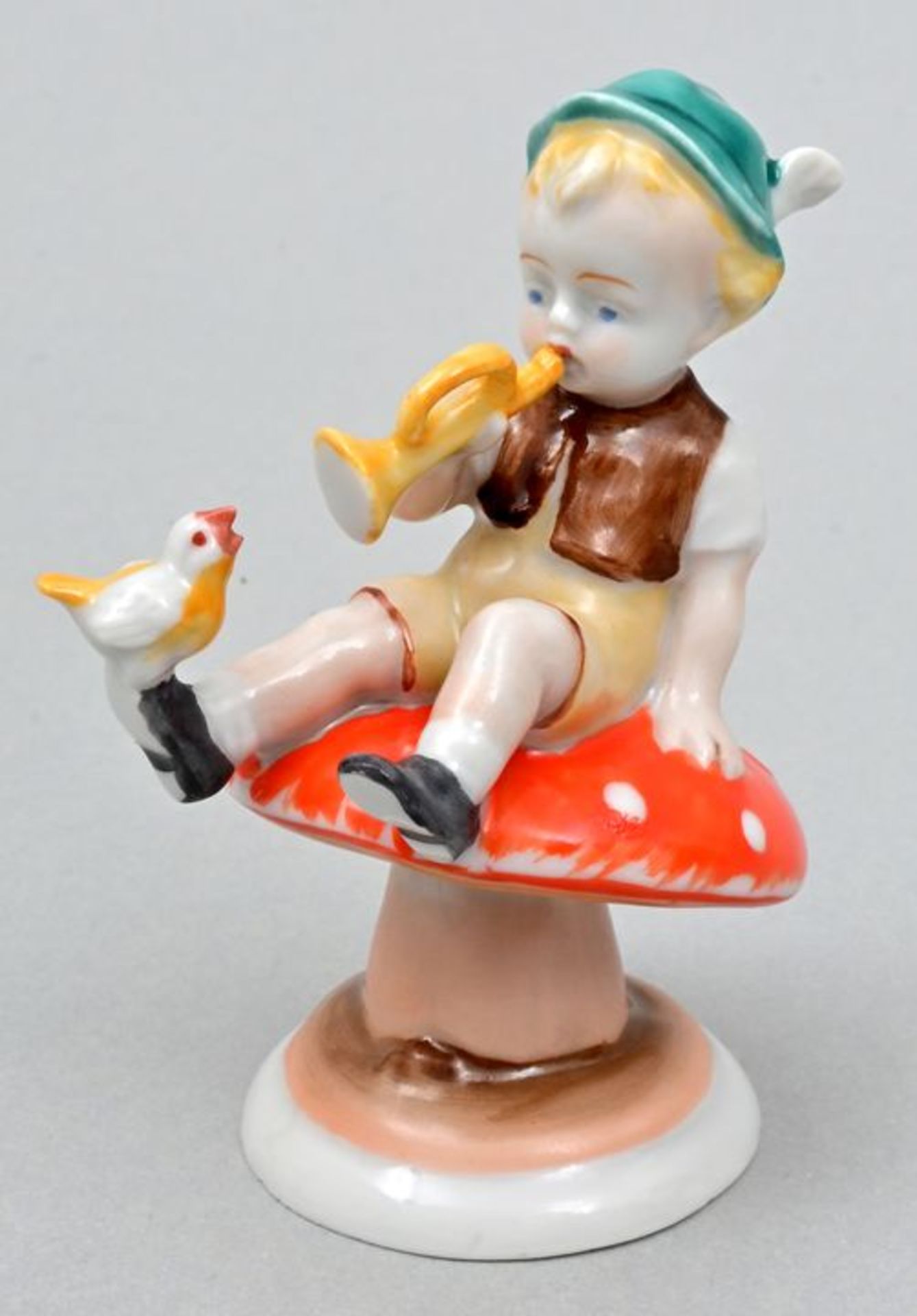 Porzellanfigur, Junge mit Tröte auf Fliegenpilz / Porcelain figure