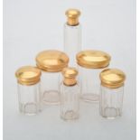 A set of six facetted glass dressing table jars with gilded caps