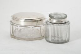 A facetted glass dressing table container with a silver coloured cover