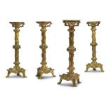 A SET OF FOUR GILT BRASS GOTHIC REVIVAL CANDLESTICKS, FRENCH OR ENGLISH
