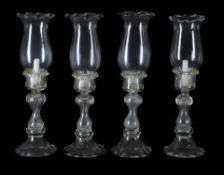 A set of four modern clear moulded glass baluster storm lights and floriform shades