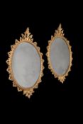 A pair of George II giltwood oval wall mirrors