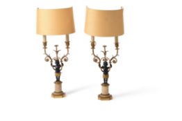 A pair of French patinated and parcel gilt metal and alabaster mounted figural candelabra