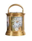 A fine French engraved gilt brass oval repeating alarm carriage clock with painted porcelain panels