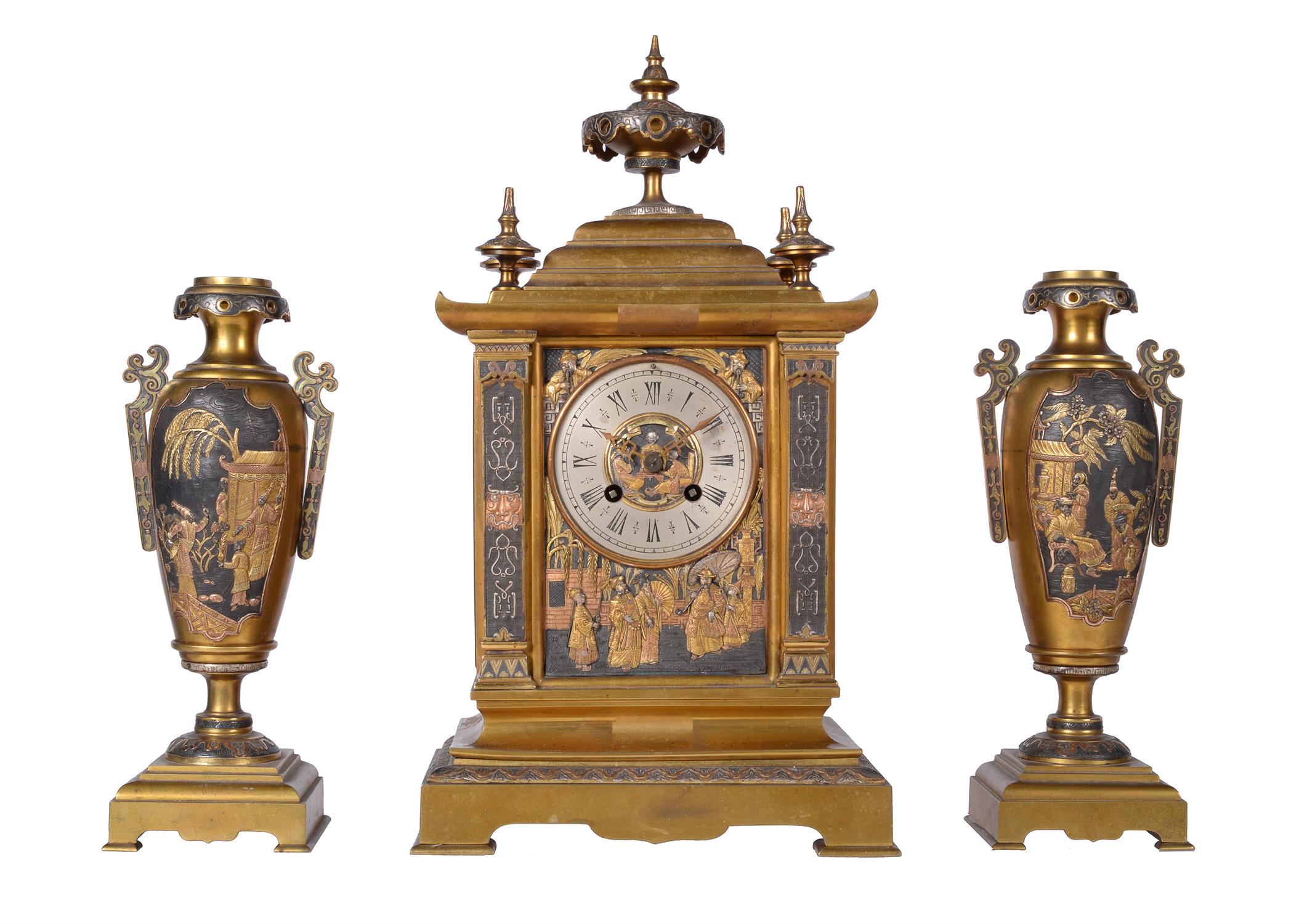 A French brass mantel clock garniture with relief cast panels