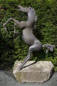 A patinated bronze garden statue of a rearing horse