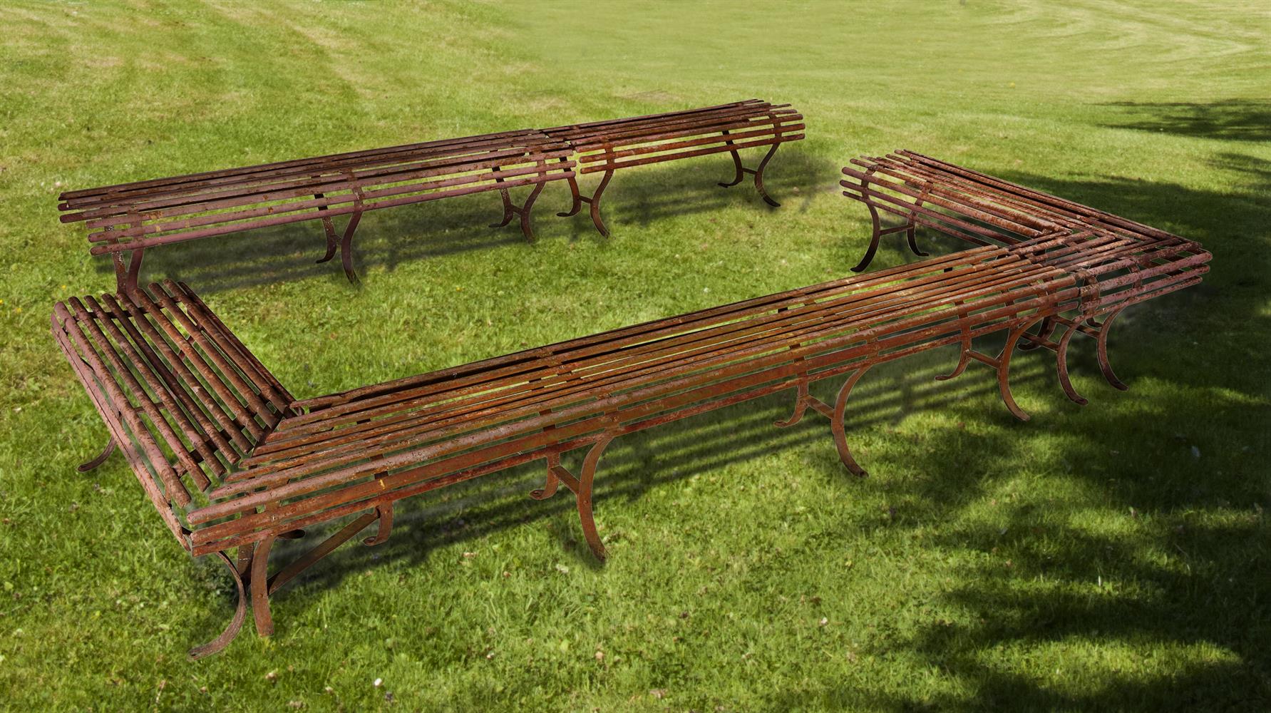 A set of five wrought iron garden benches constituting an open rectangular formation