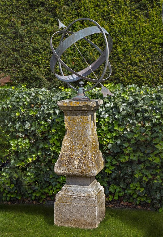 A patinated bronze mounted carved limestone armillary sphere