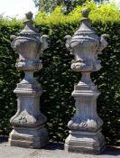 A pair of carved limestone garden urns on plinths