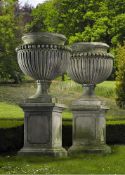 A pair of large and impressive Italian carved limestone garden urns on plinths in Impero taste