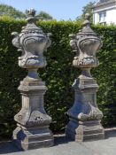 A pair of carved limestone garden urns on plinths
