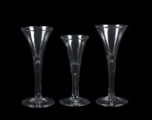 A group of three plain stemmed wine glasses of drawn trumpet form