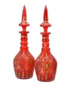 A pair of red flashed and cut glass decanters with spire shaped stoppers