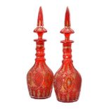 A pair of red flashed and cut glass decanters with spire shaped stoppers