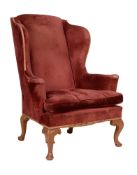 A walnut and upholstered wing armchair in George II style