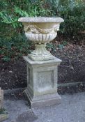 A stone composition garden urn on plinth