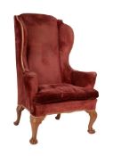 A walnut and upholstered wing armchair in early George III style