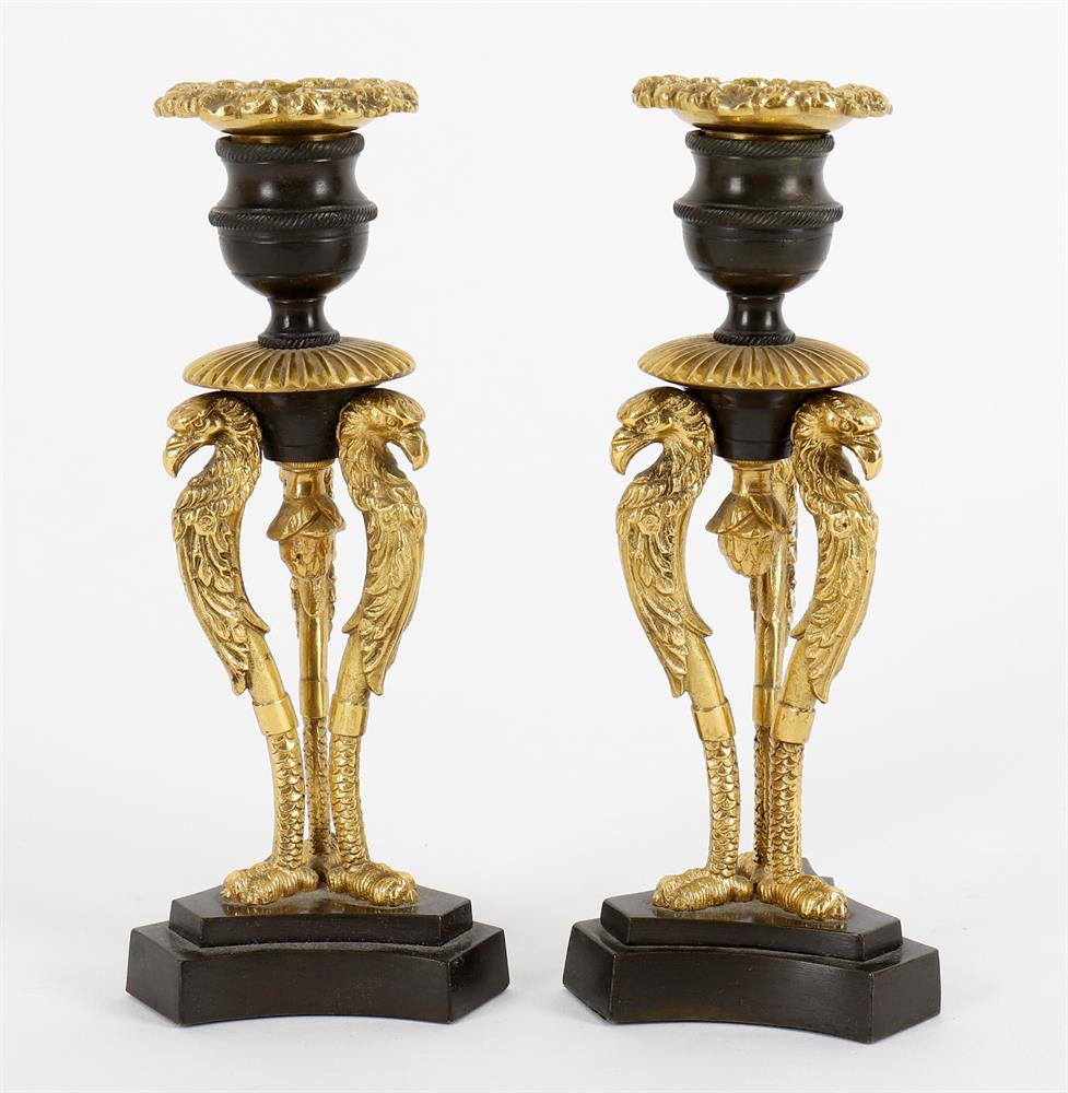 A pair of French Empire parcel gilt and patinated bronze candlesticks