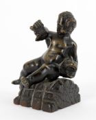 A small bronze of a seated child wrestling a dolphin and a bronze figural seal