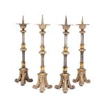 A SET OF FOUR GOTHIC REVIVAL SILVERED AND GILT METAL CANDLESTICKS