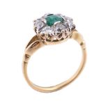 An emerald and diamond cluster ring