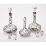 A set of three silver coloured overlaid glass bottles and stoppers