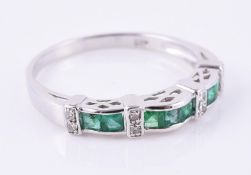 An emerald and diamond band ring
