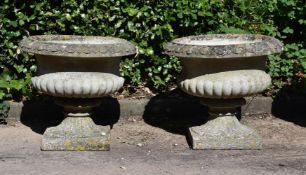 A PAIR OF COMPOSITION STONE PEDESTAL URNS, IN THE MANNER OF AUSTIN & SEELEY, EARLY 20TH CENTURY