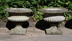 A PAIR OF COMPOSITION STONE PEDESTAL URNS, IN THE MANNER OF AUSTIN & SEELEY, EARLY 20TH CENTURY