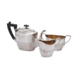 A matched Edwardian silver three piece oval half reeded three piece tea service by Joseph Rodgers &