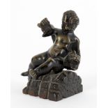A small bronze of a seated child wrestling a dolphin and a bronze figural seal
