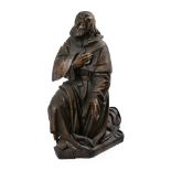 A German carved wood model of a kneeling monastic Saint