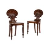 A pair of George IV carved oak shell-back hall chairs