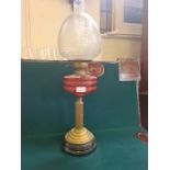 An Edwardian reeded column brass based oil lamp with cranberry bowl and etched shade.