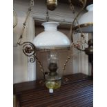 Victorian rise and fall oil lamp with decorative scrolled frame.