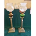 A pair of dull metal corinthium column oil lamps.