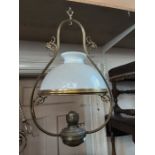 Victorian hanging oil lamping with decorative brass frame and opaque shade.