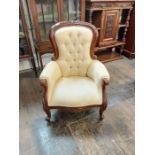 Reproduction Victorian style mahogany button back armchair with carved floral designs upon short