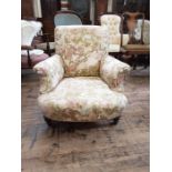 Victorian upholstered low deep seated armchair upon short turned mahogany legs with cupped brass