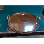 Edwardian mahogany circular tea tray with boxwood inlays, brass handles and waved gallery.