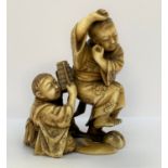 OKIMONO en ivoire figurant deux jeunes garçons, l'un jouant du xylophone, l'autre levant un pied, un