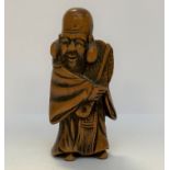 NETSUKE en bois figurant Fukurukuju debout tenant un éventail rigide d'une main. Japon, époque