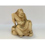 NETSUKE en ivoire sculpté d'un senin assis sur un rocher, ses robes sur l'épaule gauche (petit