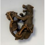 NETSUKE en bois figurant un squelette et un loup combattant, la main du squelette sur la gorge de