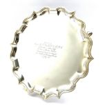 Silver circular salver with pie crust border, presentation inscription and on triple shaped supports