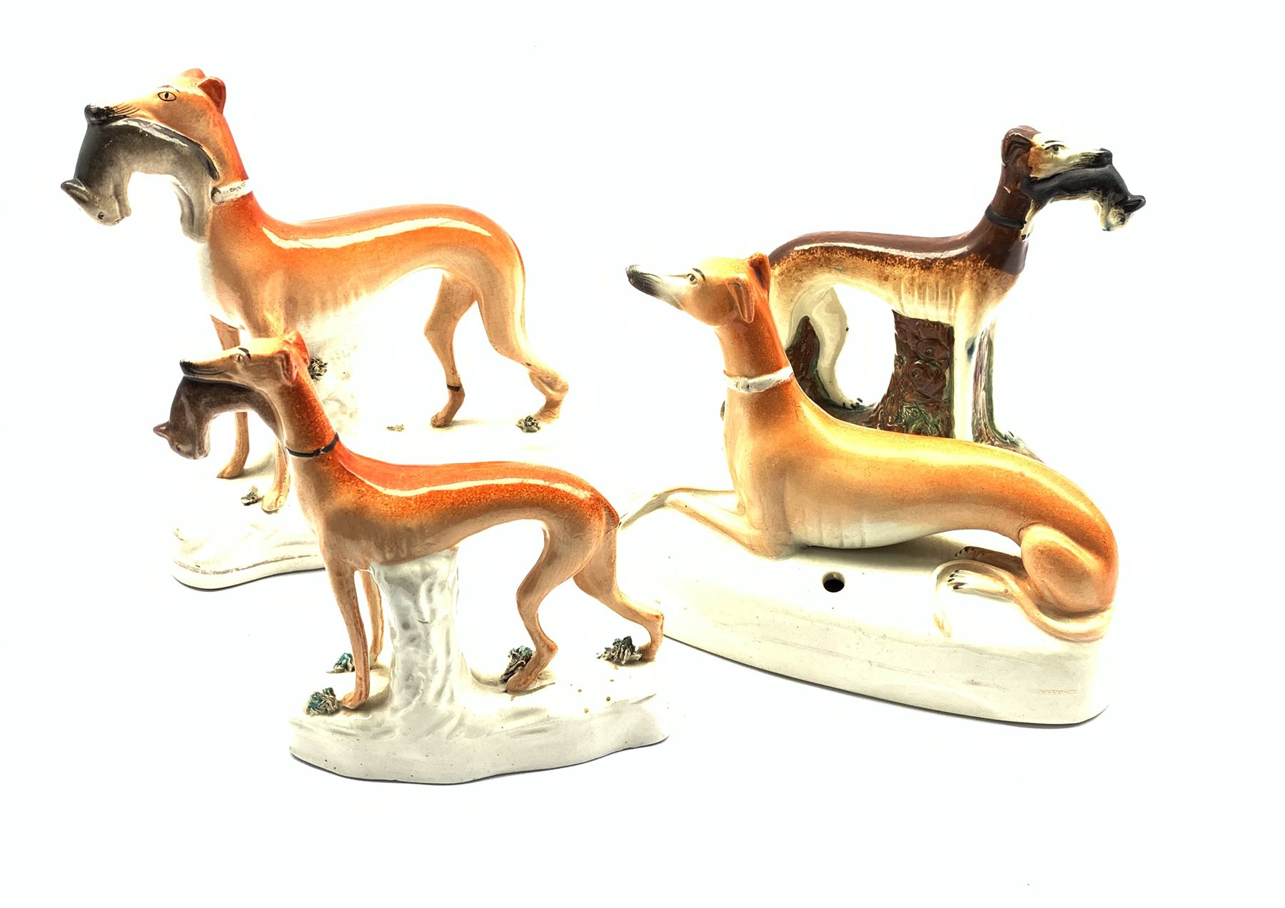 Three 19th century Staffordshire Greyhound models holding a in their mouths and another with pen sta