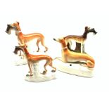 Three 19th century Staffordshire Greyhound models holding a in their mouths and another with pen sta