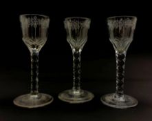 Set of three 18th century wine glasses, the ovoid bowls engraved with flower sprigs on faceted stems