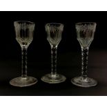 Set of three 18th century wine glasses, the ovoid bowls engraved with flower sprigs on faceted stems